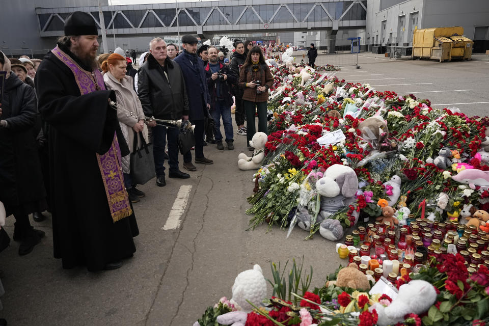 An Orthodox priest conducts a service at a makeshift memorial in front of the Crocus City Hall on the western outskirts of Moscow, Russia, Tuesday, March 26, 2024. Russian state news agency Tass says 22 victims of the concert hall attack that killed more than 130 people remain in serious condition in the hospital. (AP Photo/Alexander Zemlyanichenko)