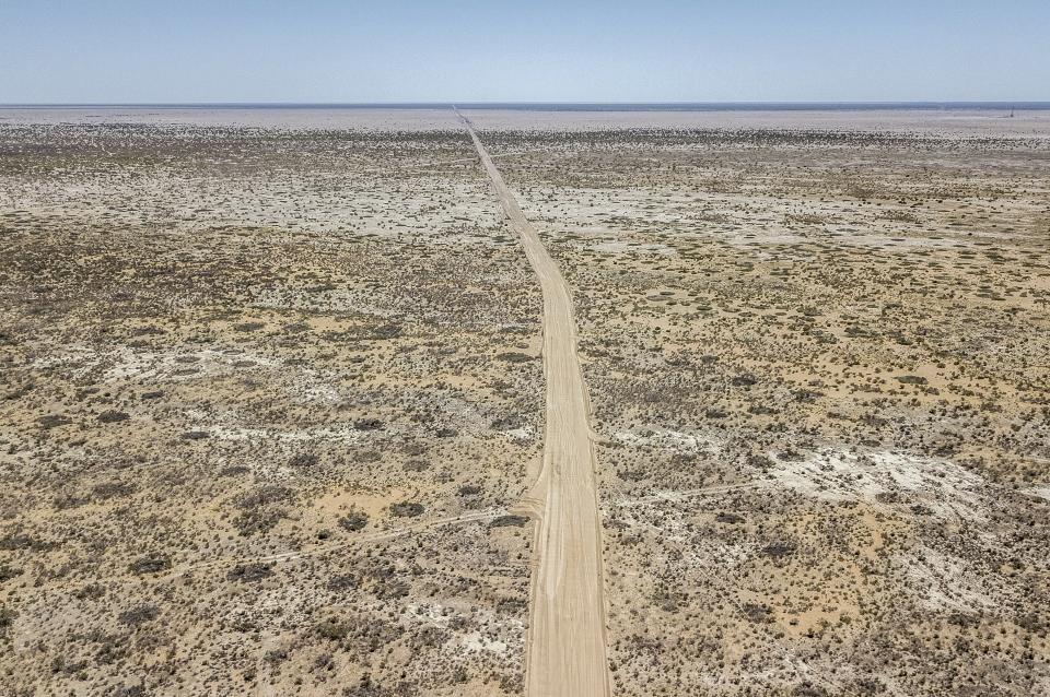 A dirt road stretches through the desert that used to be the bed of the Aral Sea, on the outskirts of Muynak, Uzbekistan, Tuesday, June 27, 2023. The drying up of the once-mighty sea has affected thousands of residents and their livelihoods for decades. (AP Photo/Ebrahim Noroozi)