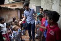 En esta imagen, tomada el 26 de agosto de 2018, Roberto Patiño saluda a niños en un centro infantil en el vecindario de La Vega, en Caracas, Venezuela. Patiño, una estrella al alza en el movimiento opositor en Venezuela, y otros organizadores de base que tienen entre 20 y 30 años han estado dando de comer a los niños, animando a las mujeres a convertirse en activistas por su comunidad y organizando protestas para exigir servicios públicos como agua potable y electricidad. (AP Foto/Ariana Cubillos)