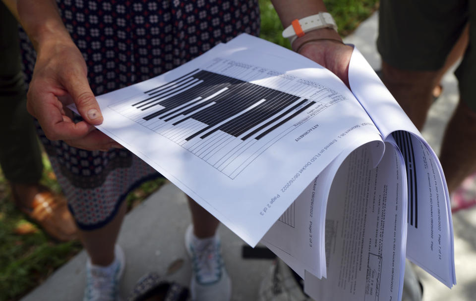 Journalists gather outside the Paul S. Rogers Federal Building and U.S. Courthouse in downtown West Palm Beach, Fla., to read a heavily blackout document released by The Justice Department Friday, Aug. 26, 2022. The 32-page affidavit, even in its heavily redacted form, offers the most detailed description to date of the government records being stored at former President Donald Trump's Mar-a-Lago property long after he left the White House and reveals the gravity of the government's concerns that the documents were there illegally. (AP Photo/Jim Rassol)