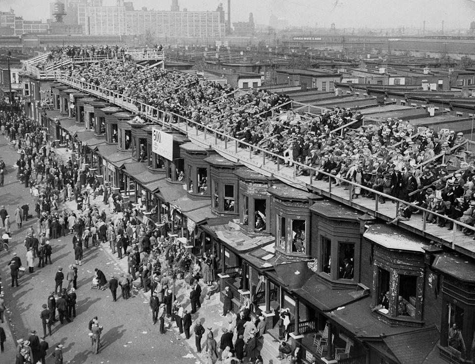 FILE - This October 1929 file photo shows baseball fans on the roofs of row houses overlooking Shibe Park to watch the Philadelphia Athletics play against the Chicago Cubs for $5.00, in Philadelphia. The windows are taken out of the second floor window frames. This week, Major League Baseball players and owners reached an agreement to play an abbreviated, 60-game season that would start July 23 or 24 in teams’ home ballparks. But the seats will be empty. Instead, fans hoping to see a game in person will be have to settle for pressing their faces up against hotel windows, squinting through metal grates or climb to rooftops when baseball returns this month in otherwise empty stadiums. (AP Photo/File)