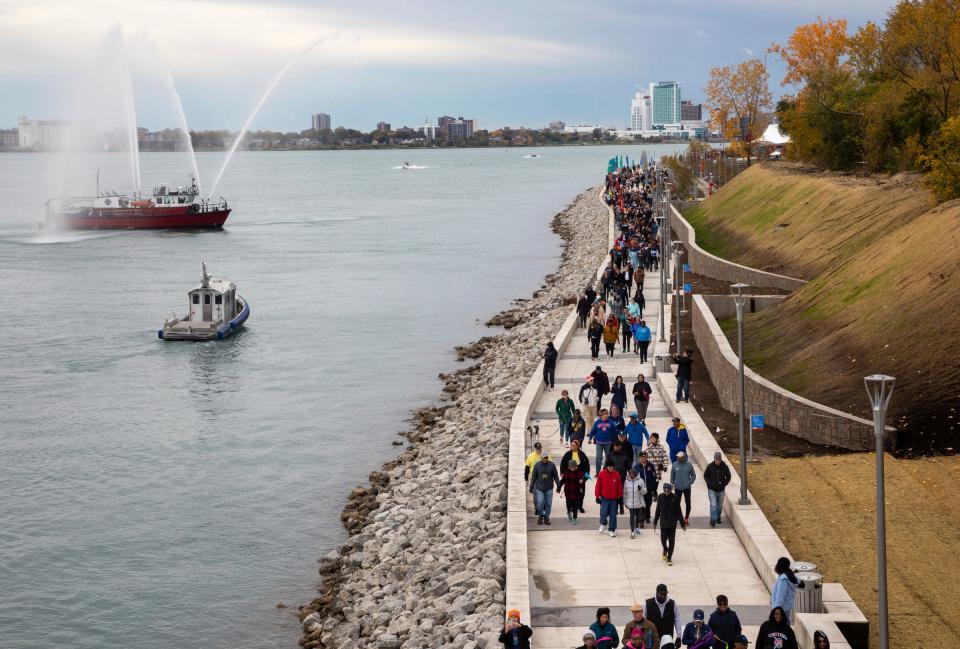 Dozens of pedestrians walk during the Uniroyal Promenade ribbon-cutting ceremony on Detroit’s Riverwalk in Detroit on Saturday, Oct. 21, 2023. The new Uniroyal Promenade completes the 3.5 mile-long Riverwalk and provides access to Belle Isle.