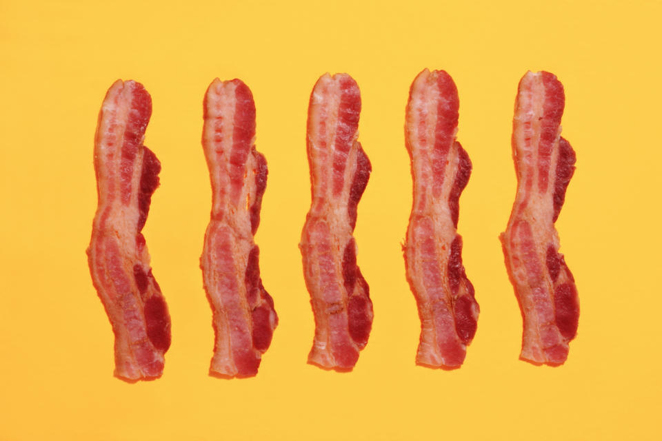 Five strips of bacon laying vertically on a blank background