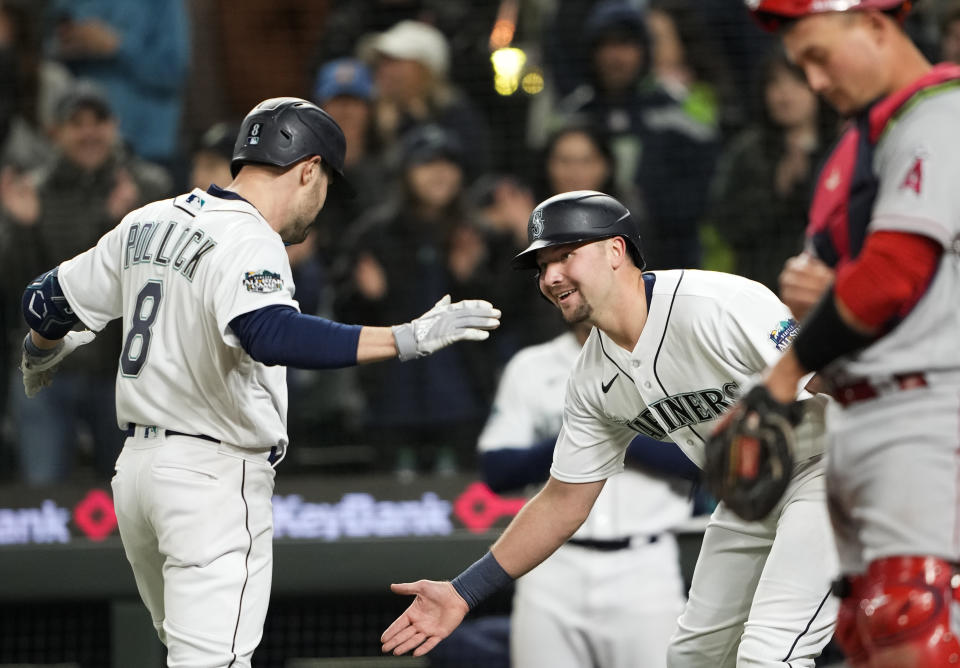 Seattle Mariners' AJ Pollock, left, greets Cal Raleigh after hitting a two-run home run to score Raleigh against the Los Angeles Angels during the seventh inning of a baseball game Tuesday, April 4, 2023, in Seattle. (AP Photo/Lindsey Wasson)