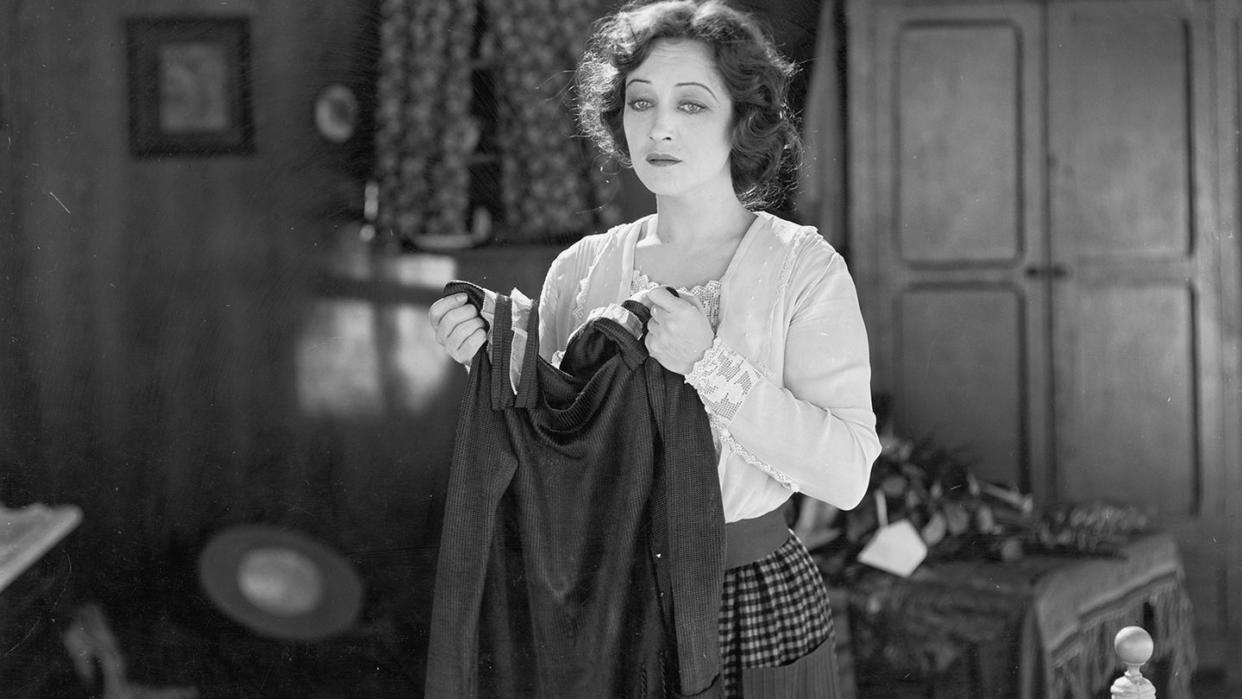 woman holds a dress and looks forlorn in an unidentified film still