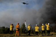 NSW Rural Fire Service crews watch on as a helicopter drops water on to protect properties on Wheelbarrow Ridge at Colo Heights, north west of Sydney