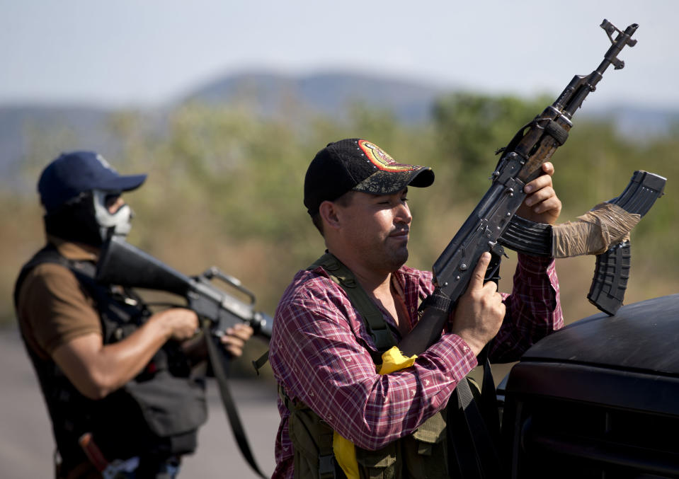 Armed men belonging to the Self-Defense Council of Michoacan, (CAM), stands guard at checkpoint at the entrance of Antunez, Mexico, Tuesday, Jan. 14, 2014. The Mexican government moved in to quell violence between vigilantes and a drug cartel, and witnesses say several unarmed civilians were killed in an early Tuesday confrontation. (AP Photo/Eduardo Verdugo)