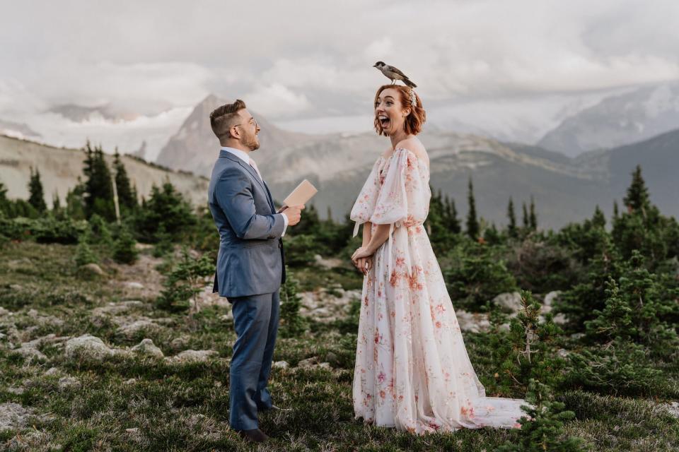 A bird lands on a bride's head during her wedding in a forest.