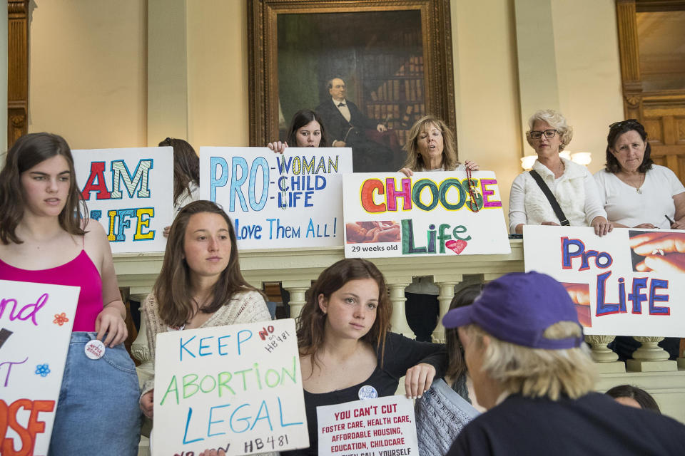 File-This March 22, 2019, file photo shows, pro-abortion rights and anti-abortion demonstrators displaying their signs in the lobby of the Georgia State Capitol building during the 35th legislative day at the Georgia State Capitol building in downtown Atlanta. Bucking intense opposition from abortion rights groups, citizens, physicians groups and even Hollywood celebrities, Georgia lawmakers gave final approval Friday, March 29, 2019, to a "heartbeat" abortion ban that would outlaw almost all abortions in the state. The proposal now heads to the desk of Republican Gov. Brian Kemp, who backs it. If enacted, it would be among the strictest abortion bans in the U.S. (Alyssa Pointer/Atlanta Journal-Constitution via AP, File)