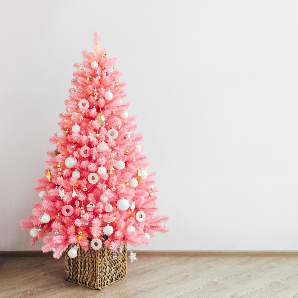 Pink christmas tree and christmas decorations white and gold color in white interior.