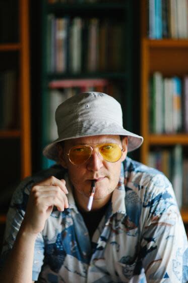 A man in a hat and sunglasses, with a cigarette holder in his mouth