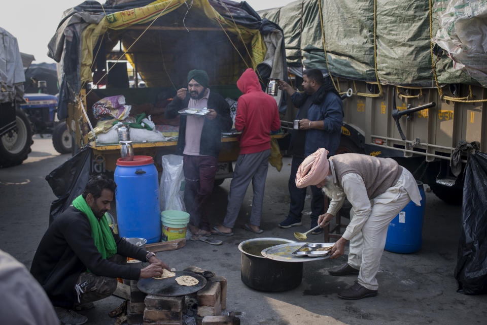 Protesting farmers eat breakfast outside their vehicles as they block a major highway during a protest to abolish new farming laws they say will result in exploitation by corporations, eventually rendering them landless, at the Delhi-Haryana state border, India, Tuesday, Dec. 1, 2020. The busy, nonstop, arterial highways that connect most northern Indian towns to this city of 29 million people, now beat to the rhythm of never-heard-before cries of "Inquilab Zindabad" ("Long live the revolution"). Tens and thousands of farmers, with colorful distinctive turbans and long, flowing beards, have descended upon its borders where they commandeer wide swathes of roads. (AP Photo/Altaf Qadri)