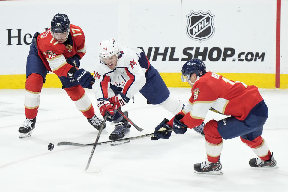 Washington Capitals defenseman John Carlson (74) battle for the puck with Florida Panthers centers Evan Rodrigues (17) and Sam Reinhart (13) during the second period of an NHL hockey game, Saturday, Feb. 24, 2024, in Sunrise, Fla. (AP Photo/Wilfredo Lee)