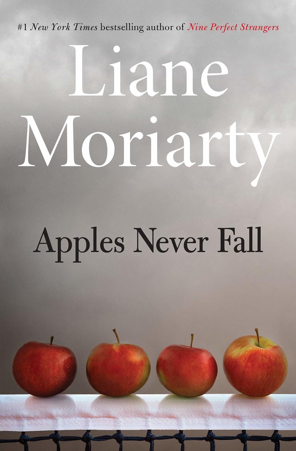 Book cover for "Apples Never Fall" by Liane Moriarty, featuring four apples on top of paper towel-covered barbed wire