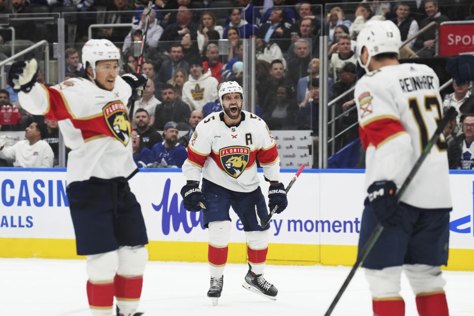 Florida Panthers defenseman Aaron Ekblad (5) and defenseman Brandon Montour celebrate a goal by forward Sam Reinhart against the Toronto Maple Leafs during the third period of an NHL hockey game in Toronto on Wednesday, March 29, 2023. (Nathan Denette/The Canadian Press via AP)