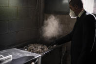 A mortuary worker collects the ashes of a COVID-19 victim from an oven after the remains where cremated at Memora mortuary in Girona, Spain, Nov. 19, 2020. The image was part of a series by Associated Press photographer Emilio Morenatti that won the 2021 Pulitzer Prize for feature photography. (AP Photo/Emilio Morenatti)