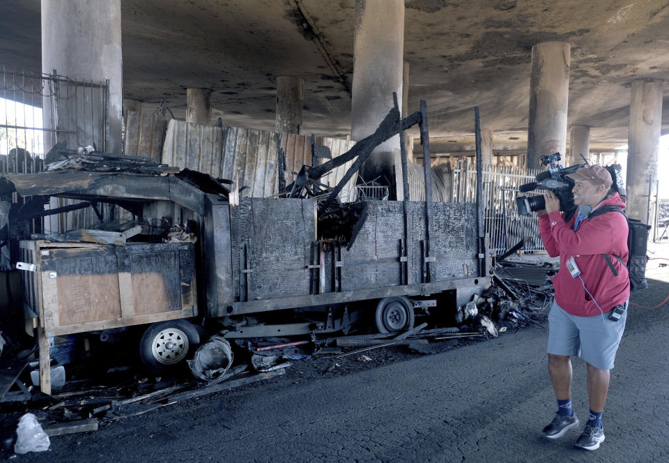 Part of a burned homeless encampment is shown as crews continue to clear debris and shore up a stretch of Interstate 10, Tuesday morning Nov. 14, 2023, in Los Angeles. It will take at least three weeks to repair the Los Angeles freeway damaged in an arson fire, the California Gov. Gavin Newsom said Tuesday, leaving the city already accustomed to soul-crushing traffic without part of a vital artery that serves hundreds of thousands of people daily. (Dean Musgrove/The Orange County Register via AP)