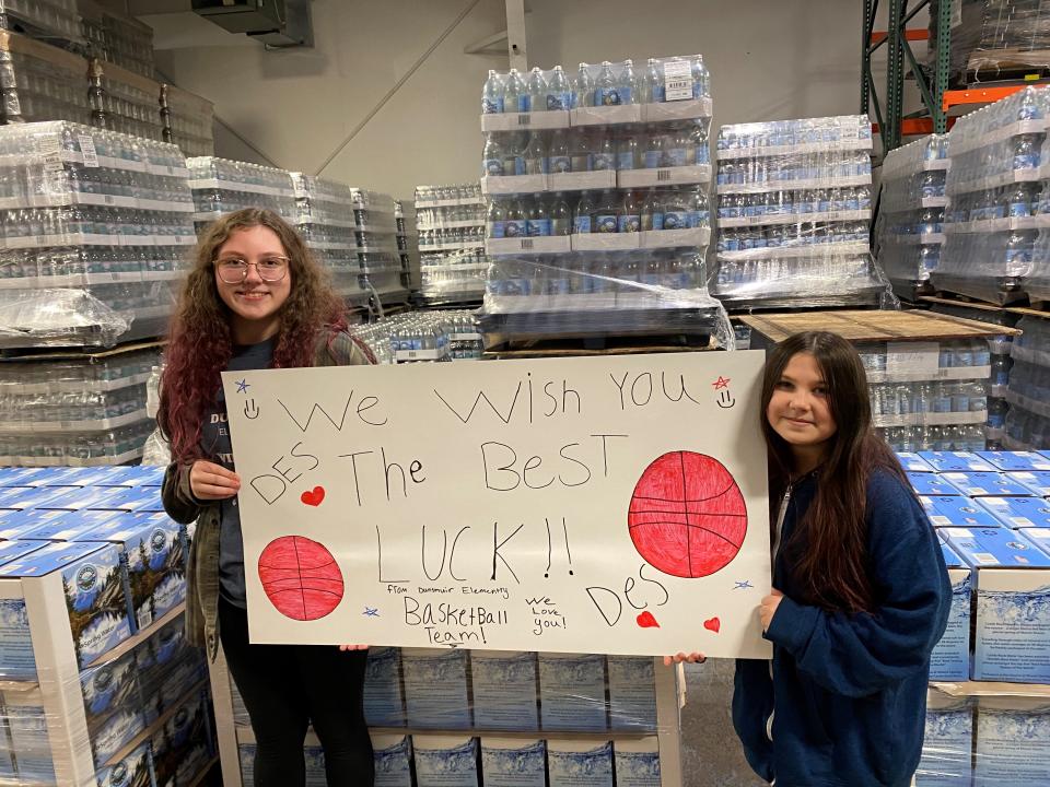 Sisters Casidee Berrigan, 13, left, and Ray Lynn Berrigan, 10,  hold up a poster they made for the people of East Palestine, Ohio from the Dunsmuir Elementary School basketball team. The poster will accompany 26 pallets of water donated by Castle Rock Water in Dunsmuir to Ohioans affected by the toxic spill from a train derailment on Feb. 3, 2023.