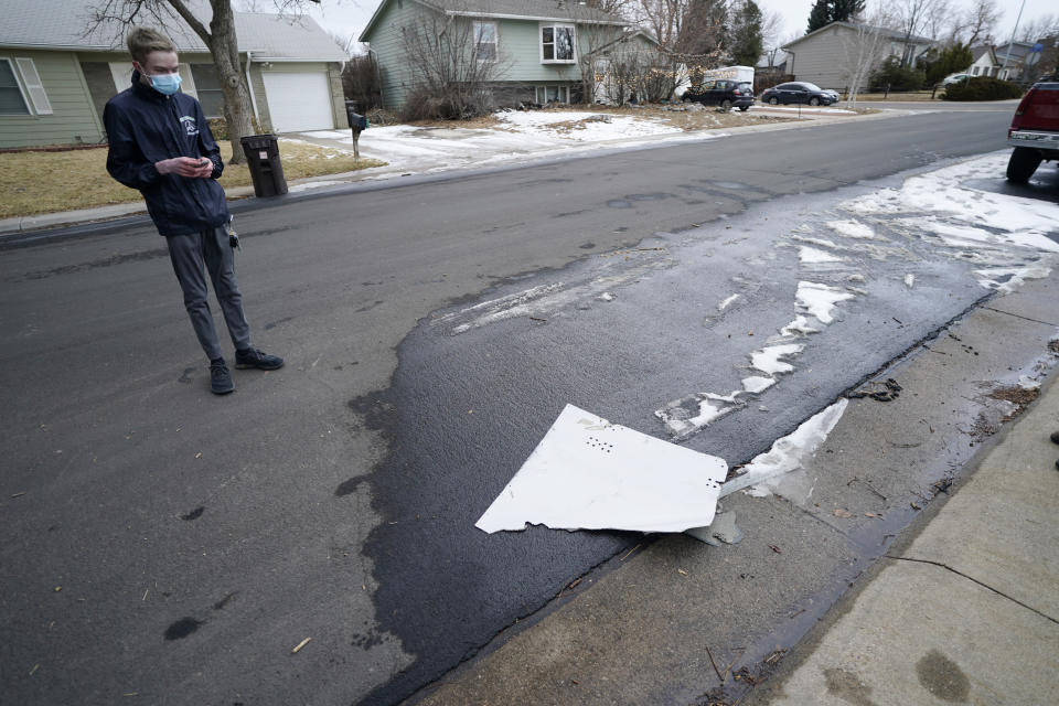 A man looks over debris that fell off a plane as it shed parts over a neighborhood in Broomfield, Colo., Saturday, Feb. 20, 2021. The plane was making an emergency landing at nearby Denver International Airport. (AP Photo/David Zalubowski)