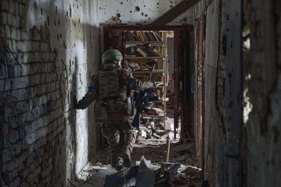 FILE - A Ukrainian soldier examines a culture center in recently retaken Blahodatne, Donetsk region, Ukraine, Friday, June 16, 2023. Ukraine's June 10 recapture of the small village of Neskuchne in the eastern Donetsk region encapsulates the progress of its much-anticipated counteroffensive: small platoon-sized operations banking on the element of surprise and, when successful, notching incremental territorial gains. (AP Photo/Libkos, File)