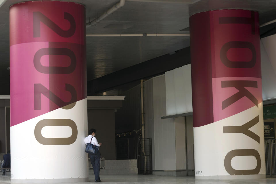 A man stands at a pillar with advertisement of Tokyo 2020 Olympic and Paralympic Games at a train station near the National Stadium in Tokyo Wednesday, June 9, 2021. Roads were being closed off since last Tuesday around Tokyo Olympic venues, including the new $1.4 billion National Stadium where the opening ceremony is set for July 23. (AP Photo/Eugene Hoshiko)