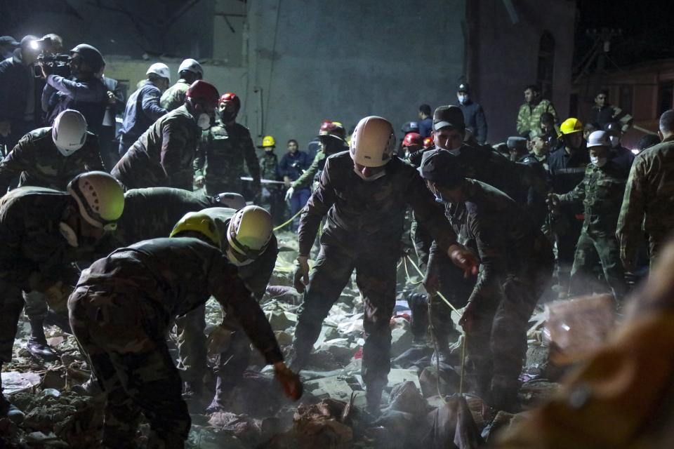 Soldados y bombertos buscan sobrevivientes en una zona residencial alcanzada por un misil armenio el sábado 17 de octubre de 2020 en Gyanga, la segunda ciudad de Azer4baiyán, en la frontera con Armenia. (AP Foto/Aziz Karimov)