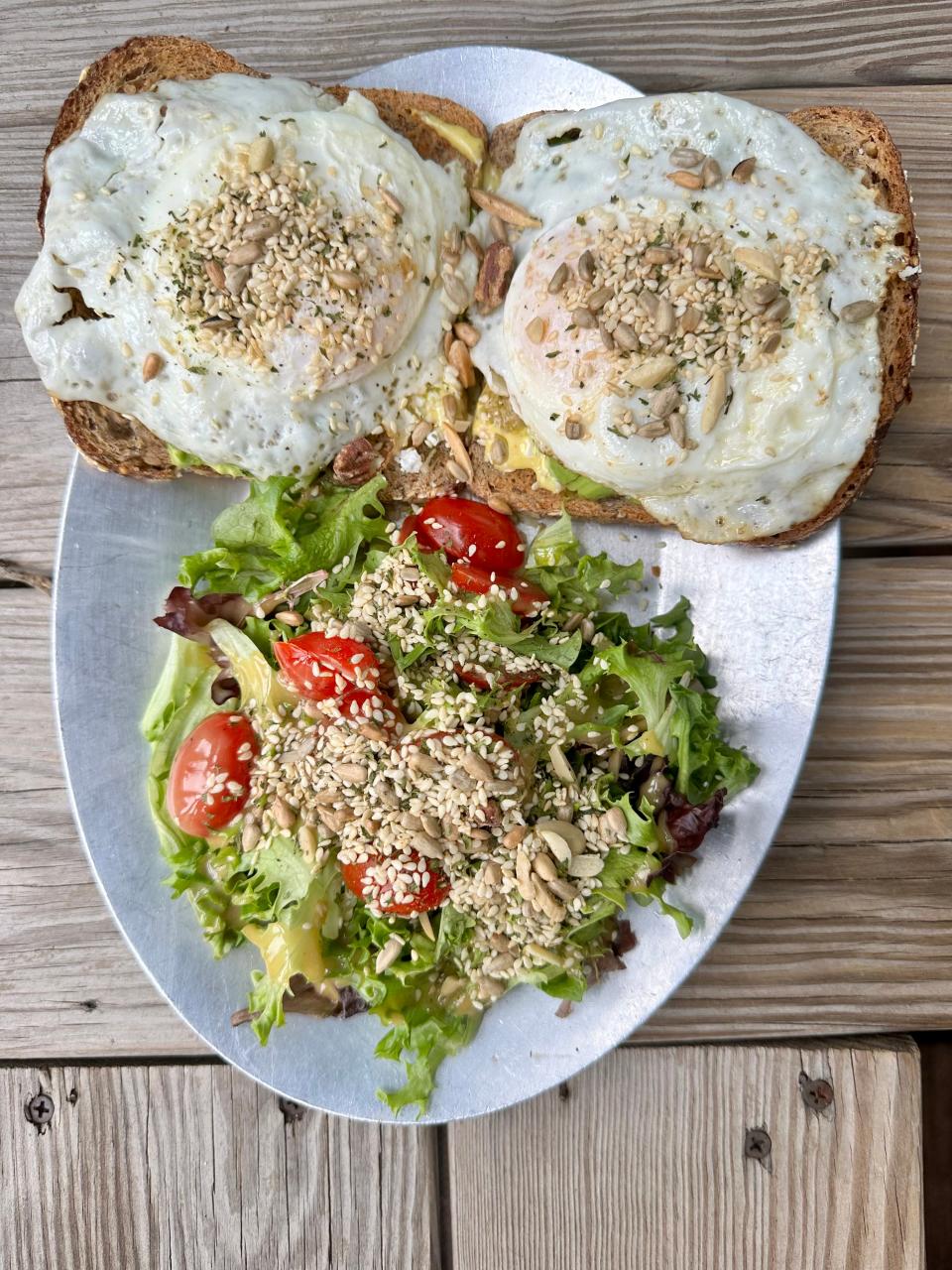 Toast and salad at Art Cafe in Nyack. The restaurant, also known for its toastinis, features its avocado toast dressed with olive tapenade, an over easy egg, and Bulgarian feta topped with a seed and nut mix.