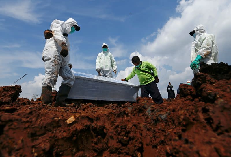 FILE PHOTO: Municipality workers, wearing personal protective equipment (PPE), prepare to bury the coffin of a COVID-19 victim in Jakarta