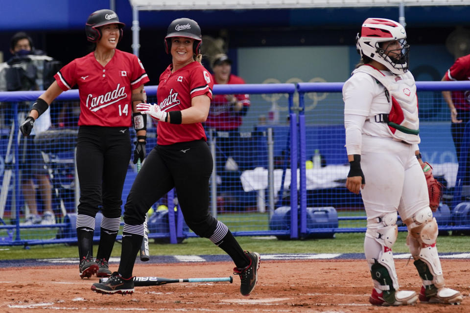 Canada's Erika Polidori, center scores past Mexico catcher Sashel Palacios as Canada's Janet Leung (14) looks on during a softball game at the 2020 Summer Olympics, Tuesday, July 27, 2021, in Yokohama, Japan (AP Photo/Sue Ogrocki)