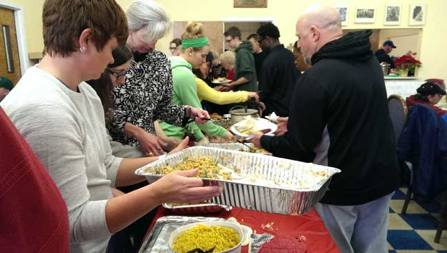 Volunteers prepare plates of food for guests on Christmas morning in 2013 at Our Lady of the Road, the St. Peter Claver Catholic Worker's drop-in center on Main Street in South Bend.