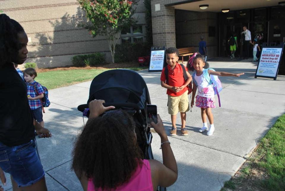 FILE - Angelena Bennett takes a photo of her son, first-grader Joseph Bennett, and her daughter, kindergartner Jasmine Bennett, outside River Ridge Elementary on the first day of school for students. River Ridge scored high marks on multiple factors of the most recent version of Georgia's College and Career Ready Performance Index.