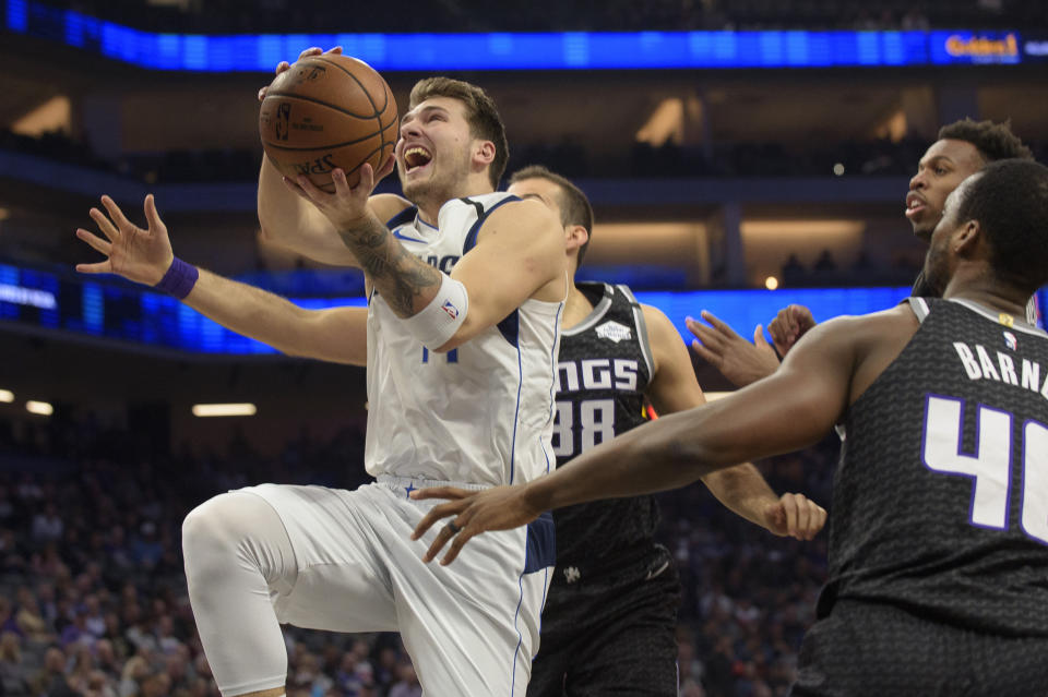 Dallas Mavericks forward Luka Doncic (77) drives to the basket past Sacramento Kings forward Nemanja Bjelica (88) and forward Harrison Barnes (40) during the first quarter of an NBA basketball game in Sacramento, Calif., Wednesday, Jan. 15, 2020. (AP Photo/Randall Benton)