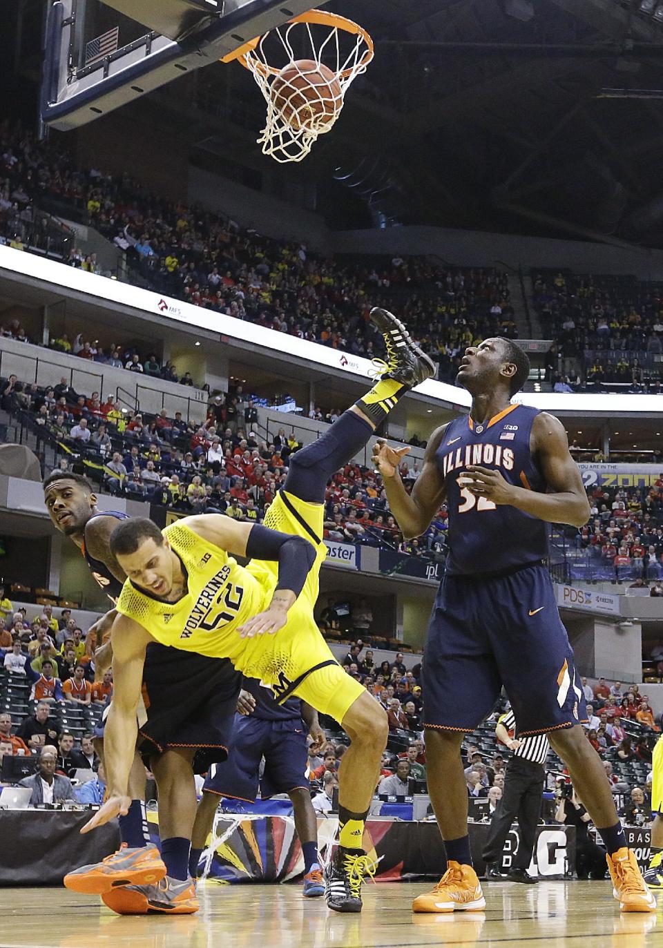 Michigan forward Jordan Morgan falls to the floor after scoring a basket against Illinois guard Rayvonte Rice, left, and center Nnanna Egwu in the first half of an NCAA college basketball game in the quarterfinals of the Big Ten Conference tournament Friday, March 14, 2014, in Indianapolis. (AP Photo/Michael Conroy)