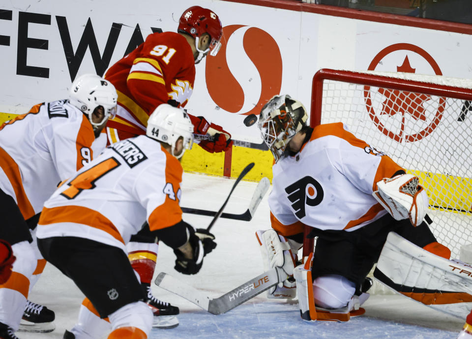 Philadelphia Flyers goalie Samuel Ersson, right, blocks a shot by Calgary Flames forward Nazem Kadri, center, during second-period NHL hockey game action in Calgary, Alberta, Monday, Feb. 20, 2023. (Jeff McIntosh/The Canadian Press via AP)