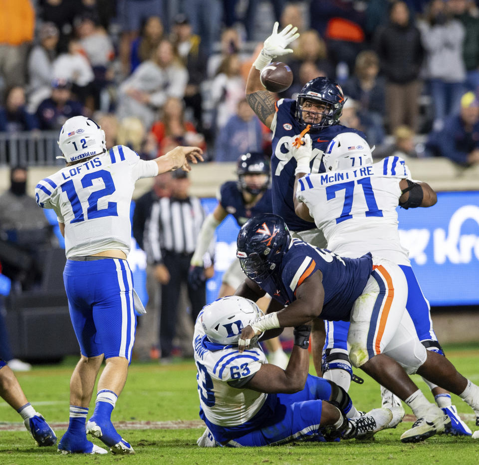 Duke quarterback Grayson Loftis (12) throws a pass as Virginia defensive tackle Aaron Faumui (94) tries to knock it down during the second half of an NCAA college football game Saturday, Nov. 18, 2023, in Charlottesville, Va. (AP Photo/Mike Caudill)