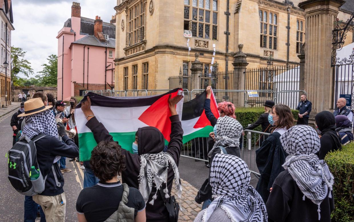 Protesters hold Palestine flags as they walk outside the Exam Schools at Oxford University