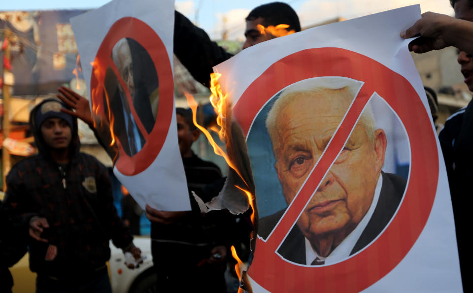 Palestinians burn a poster of the former Israel Prime Minister Ariel Sharon in Khan Younis, southern Gaza Strip, Saturday, Jan. 11, 2014. Sharon was loathed by many Palestinians as a bitter enemy who did his utmost to sabotage their independence hopes — by leading military offensives against them in Lebanon, the West Bank and Gaza and a settlement drive on the lands they want for a state. Sharon died Saturday, eight years after a debilitating stroke put him into a coma. He was 85. (AP Photo/Hatem Moussa)