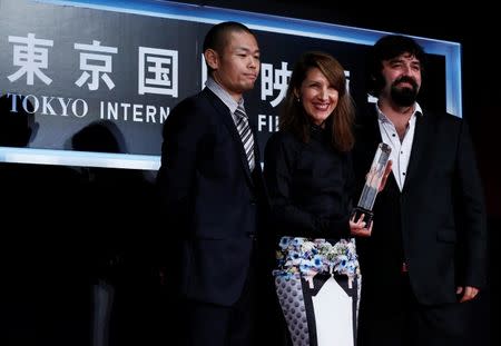 Actress Margita Gosheva (C) pose for a picture with director Petar Valchanov (R) as they receive the Special Jury Prize for their film "The Lesson" during the closing ceremony of the Tokyo International Film Festival in Tokyo October 31, 2014. Standing on stage is jury member and director Hiroshi Shinagawa. REUTERS/Yuya Shino