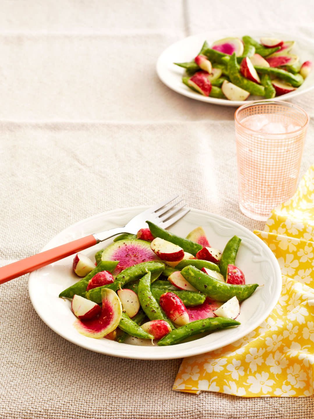 sugar snap pea and radish salad on a white plate with a fork