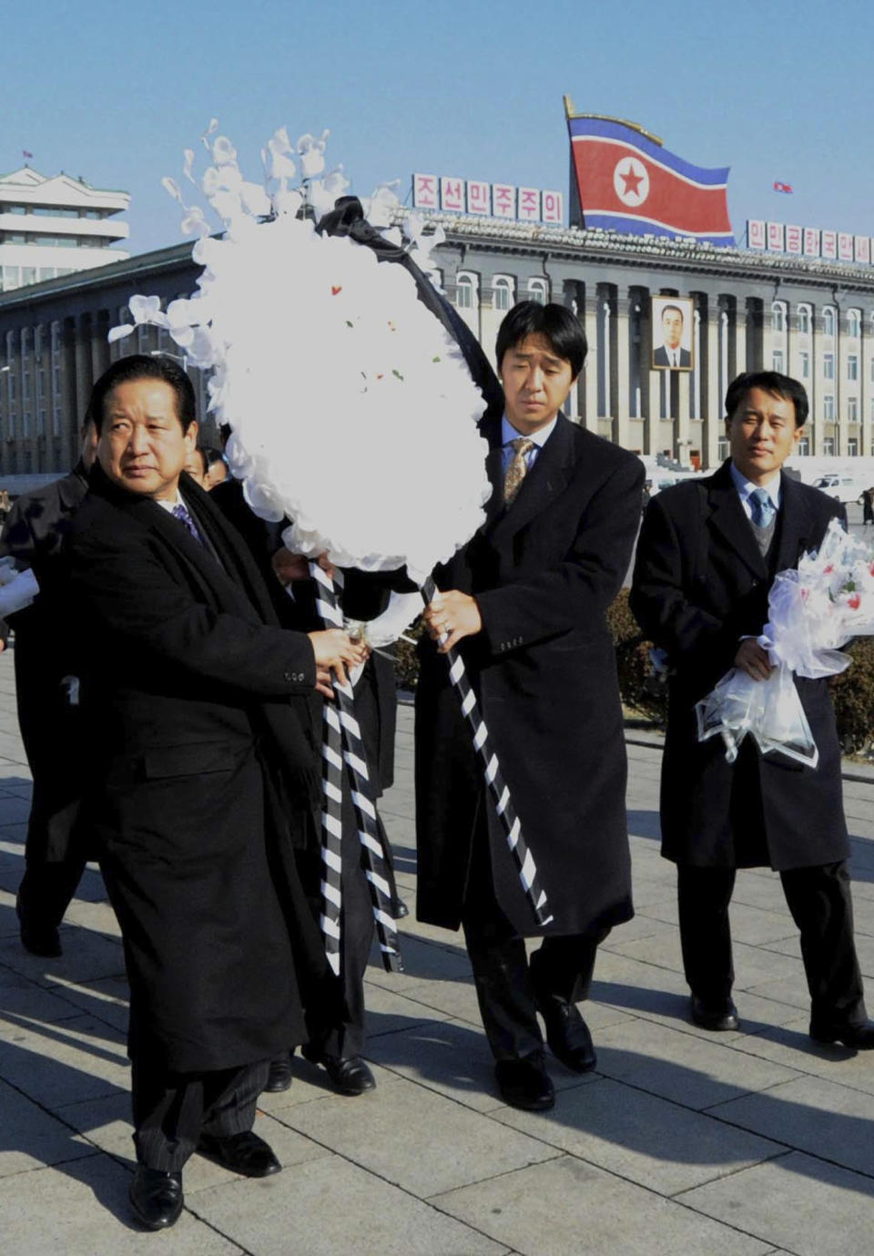 FILE - In this Dec. 24, 2011 file photo, the Rev. Hyung-jin Moon, youngest son of the Rev. Sun Myung Moon and president of the Unification Church, second from right, carries a wreath with unidentified men to lay in front of a portrait of the late Kim Jong Il at Kim Il Sung Square in Pyongyang, North Korea. Moon's U.S.-born youngest son, Hyung-jin Moon, was named the church's top religious director in April 2008. Other children run the church's businesses and charitable activities. Hyung-jin Moon told The Associated Press in February 2010 that his father's offspring do not see themselves as his successors. "Our role is not inheriting that messianic role," he said. "Our role is more of the apostles ... where we become the bridge between understanding what kind of lives (our) two parents have lived." (AP Photo/File)