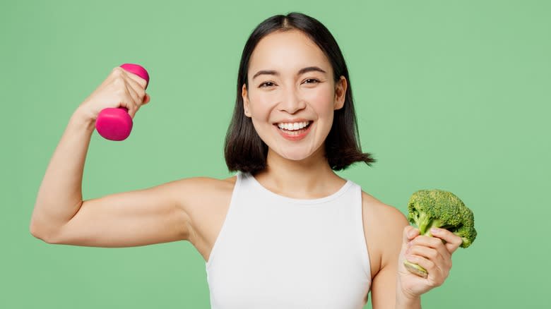 Woman holding broccoli and exercising