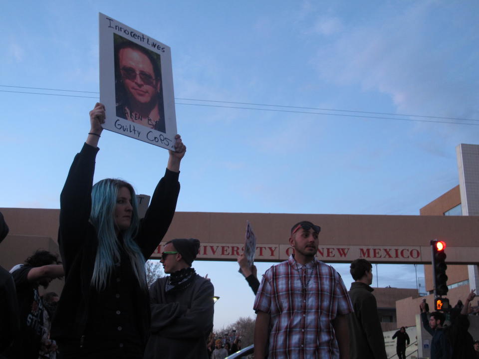 Protesters block traffic Sunday March 30, 2014, in front of the University of New Mexico in Albuquerque, N.M. during a rally against recent police shootings. Hundreds of protesters marched past riot police in Albuquerque on Sunday, days after a YouTube video emerged threatening retaliation for a recent deadly police shooting. The video, which bore the logo of the computer hacking collective Anonymous, warned of a cyber attack on city websites and called for the protest march. (AP Photo/Russell Contreras)