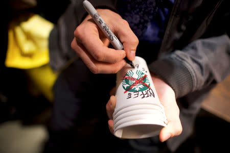 A protestor writes an anti-Starbucks message on a coffee cup while demonstrating inside a Center City Starbucks, where two black men were arrested, in Philadelphia, Pennsylvania U.S., April 16, 2018. REUTERS/Mark Makela