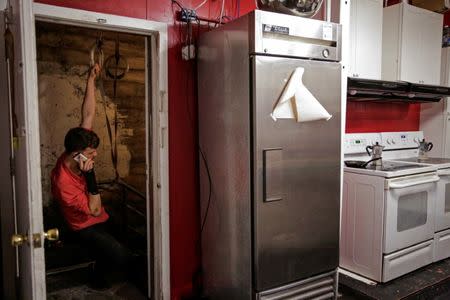 Andrew Bresee, 26, a software engineer and resident at The Negev tech house hangs from a gymnastic ring while making a phone call before joining a Sunday "family" dinner in San Francisco, California, U.S. October 30, 2016. Residents at the house cook and eat food together once a week. REUTERS/Gabrielle Laurie