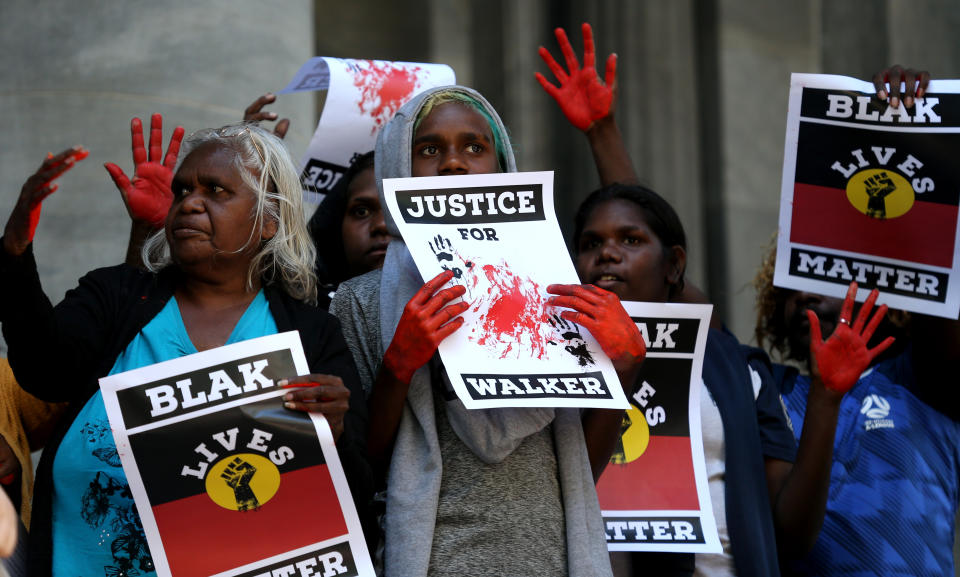 Aboriginal and Torres Strait Islanders communities and allies hold placards during a protest outside the South Australian Parliament in Adelaide, Wednesday, November 13, 2019. Aboriginal and Torres Strait Islander communities and allies are calling for justice for 19-year-old Warlpiri teenager Kumanjayi Walker, who died after being shot by police on Saturday night in the central desert town of Yuendumu in the Northern Territory. (AAP Image/Kelly Barnes) NO ARCHIVING