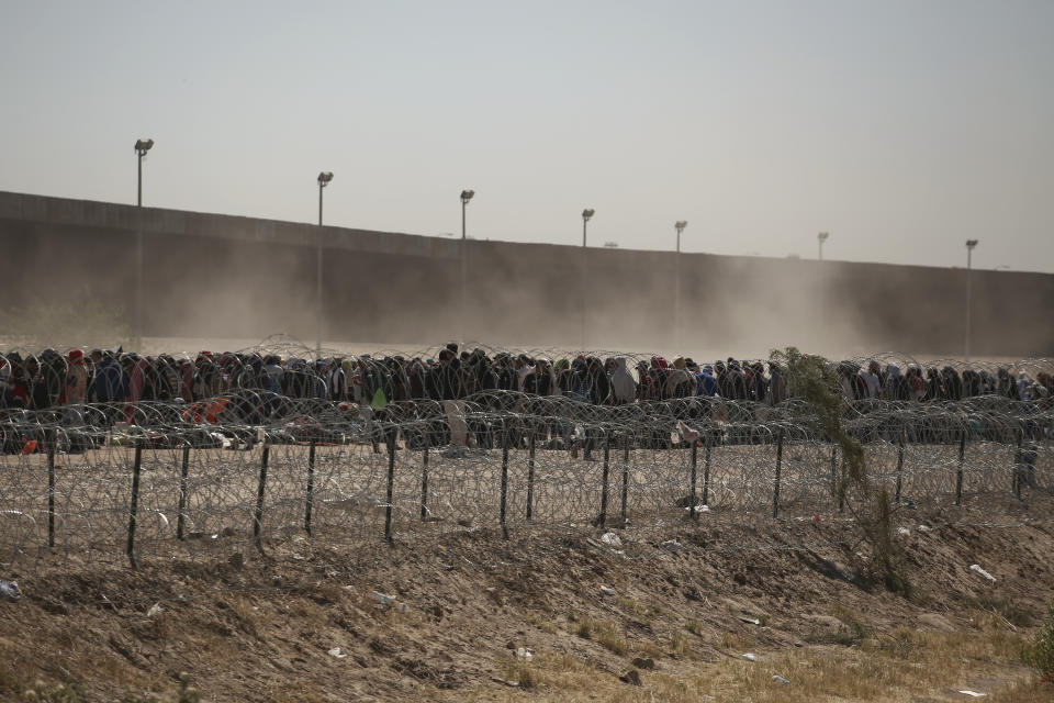 FILE - Migrants line-up between a barbed-wire barrier and the border fence at the US-Mexico border, as seen from Ciudad Juarez, Mexico, May 9, 2023. Unwittingly, migrants in Latin America finance disinformation during their journeys to the U.S., as they fall victim to fraud that can cost them thousands of dollars and that in turn has served to develop new business models, from fake work recruiters to those who call themselves "migration coaches." (AP Photo/Christian Chavez, File)