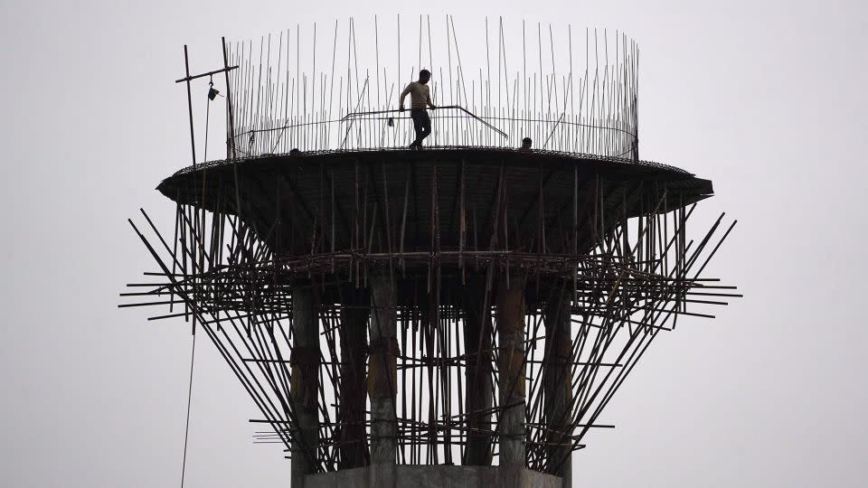 A construction worker carries metal rods during the construction of an elevated water tank in Ajmer, Rajasthan, on January 30, 2024. - Himanshu Sharma/AFP/Getty Images