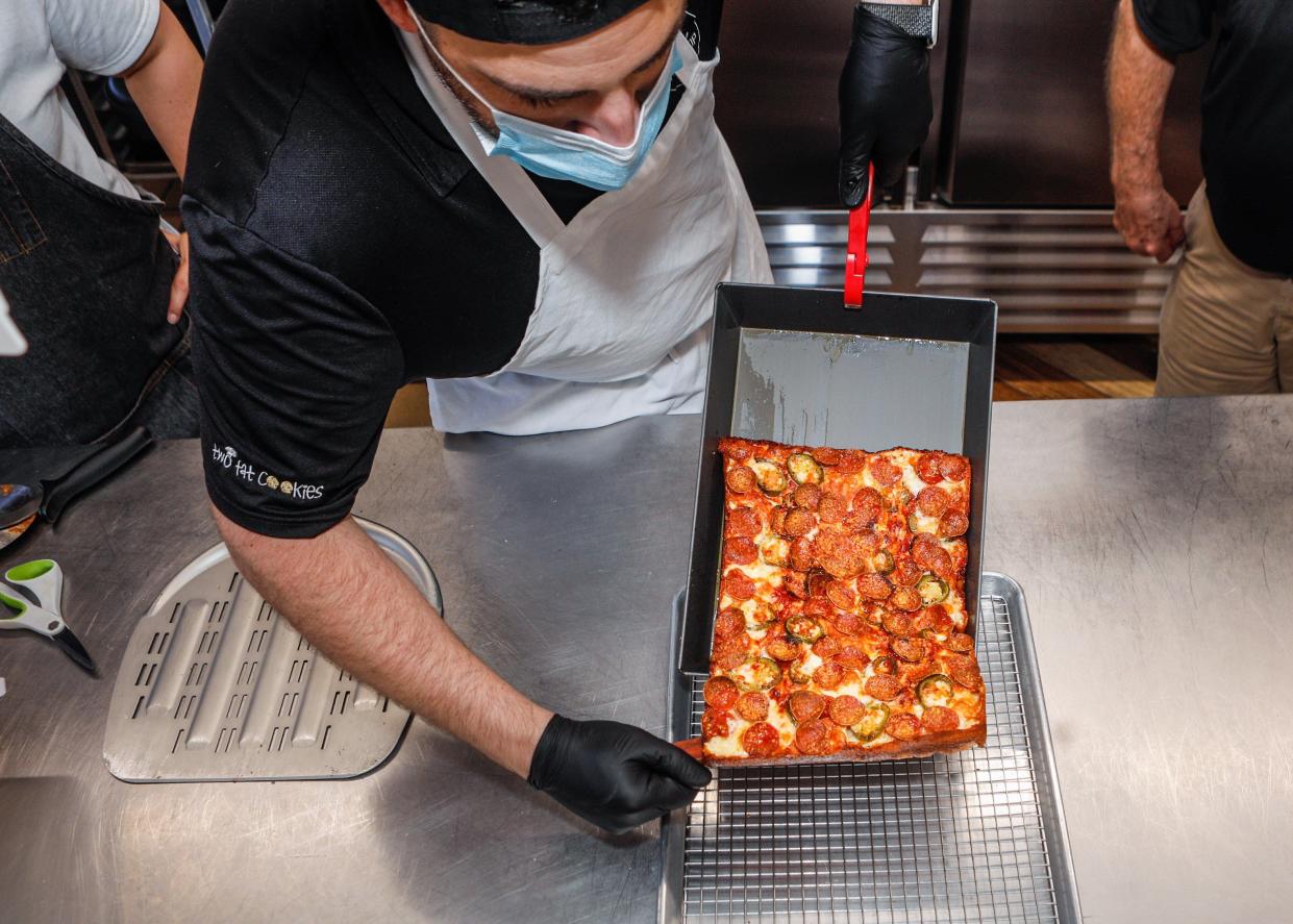 Koby Wexler, the originator of Death by Pizza in Delray Beach, slides a handmade Detroit-style pizza from a hot pan.