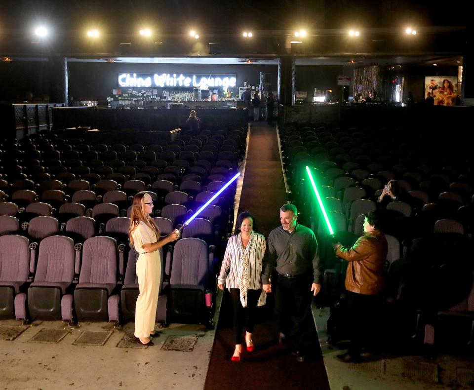 Ashly Bitter and Michael Codispoti walk under lightsabers as they head down the Highland Theater isle to be married by Akron Municipal Court Judge Ron Cable in a Star Wars themed wedding on Wednesday, May 4, 2022 in Akron.