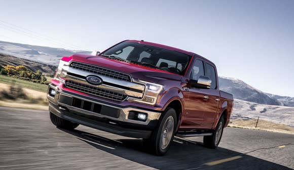 A red 2018 Ford F-150 pickup on a country road.